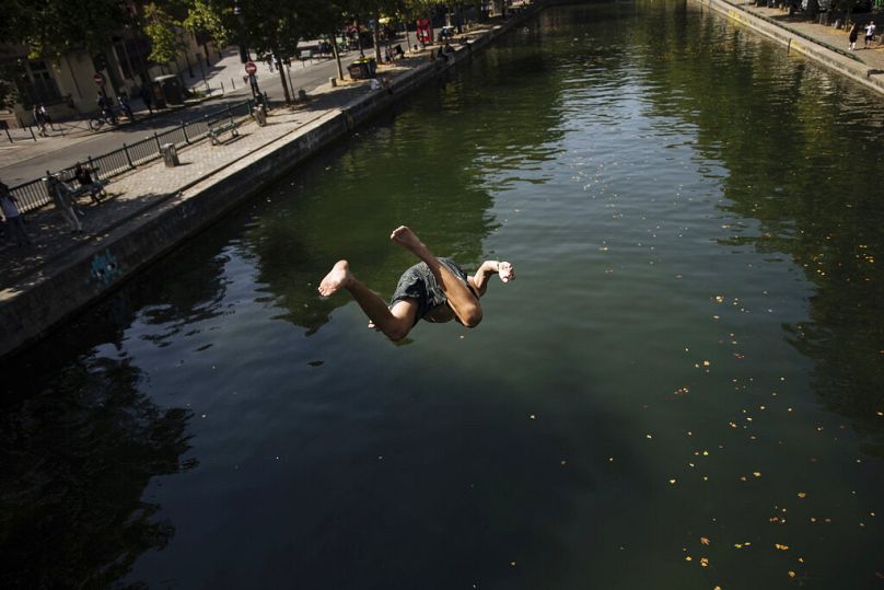 Des enfants sautent d'un pont pour nager dans le canal Saint-Martin, lors d'une canicule à Paris, juillet 2022
