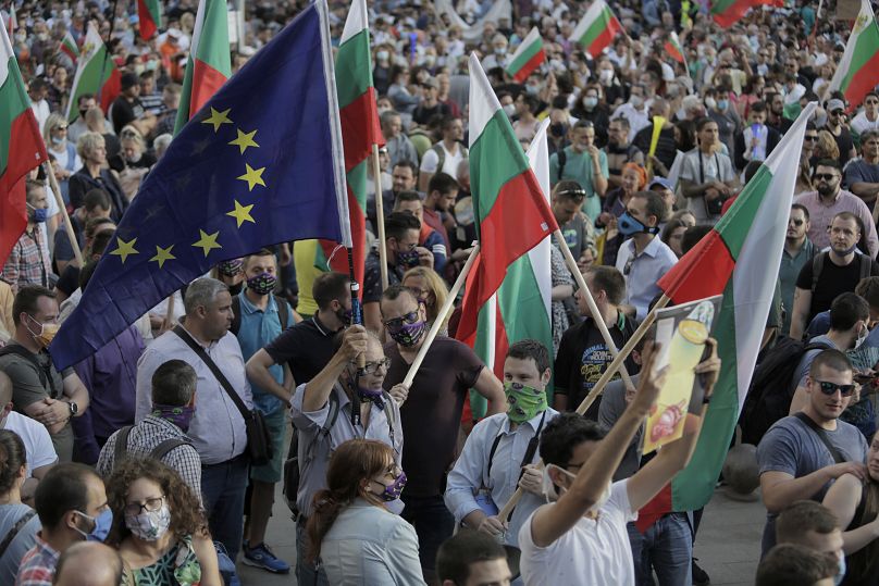 Des manifestants brandissent des drapeaux bulgares et européens alors qu'ils participent à une manifestation antigouvernementale dans le centre-ville de Sofia, le lundi 13 juillet 2020.