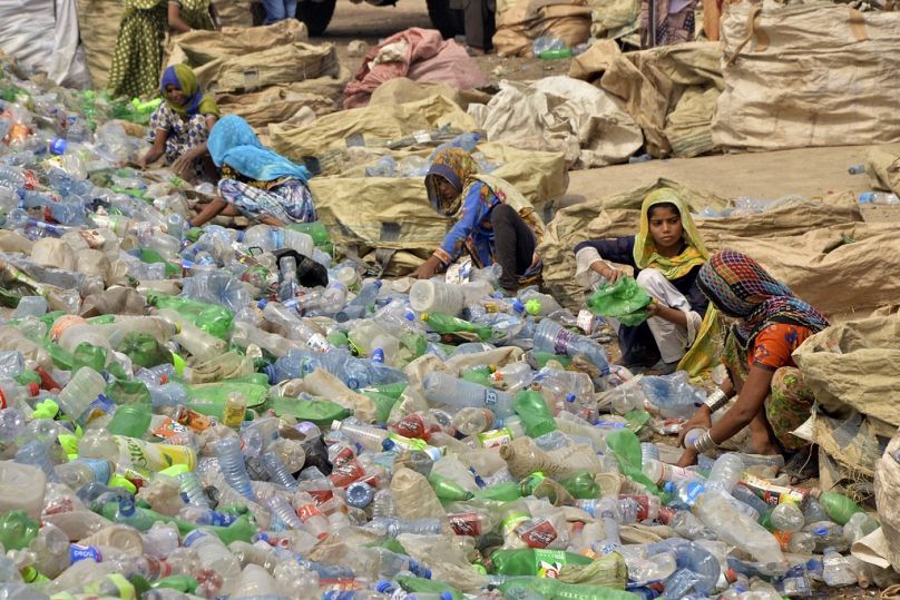 Des ouvriers pakistanais, principalement des femmes, trient des bouteilles vides dans une usine de recyclage de plastique à Hyderabad, mai 2023.