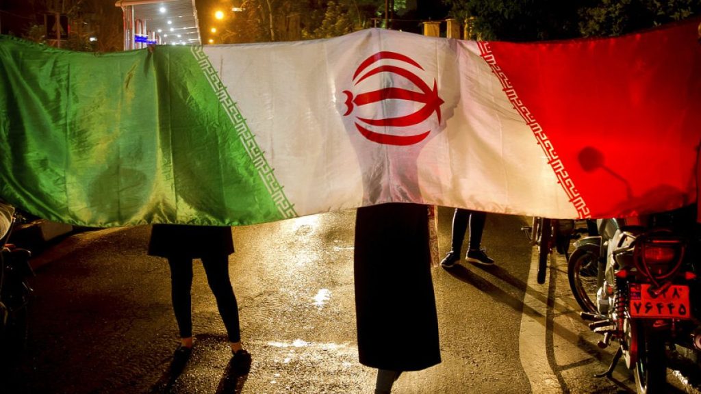 FILE - Iranians with their national flag.