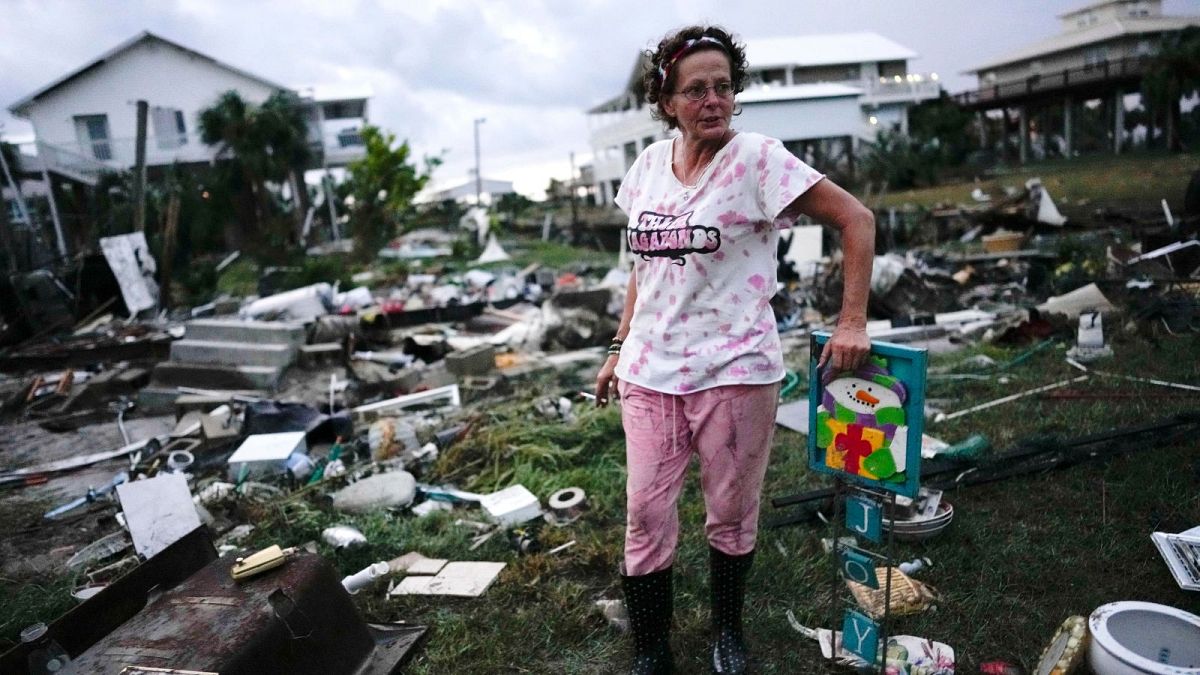 A woman stands beside the wreckage of her mother