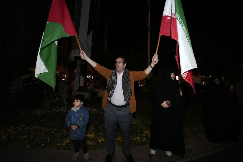 Un manifestant brandit des drapeaux iraniens et palestiniens lors d’un rassemblement anti-israélien sur la place Felestin (Palestine) à Téhéran, en Iran, tôt le dimanche 14 avril 2024.