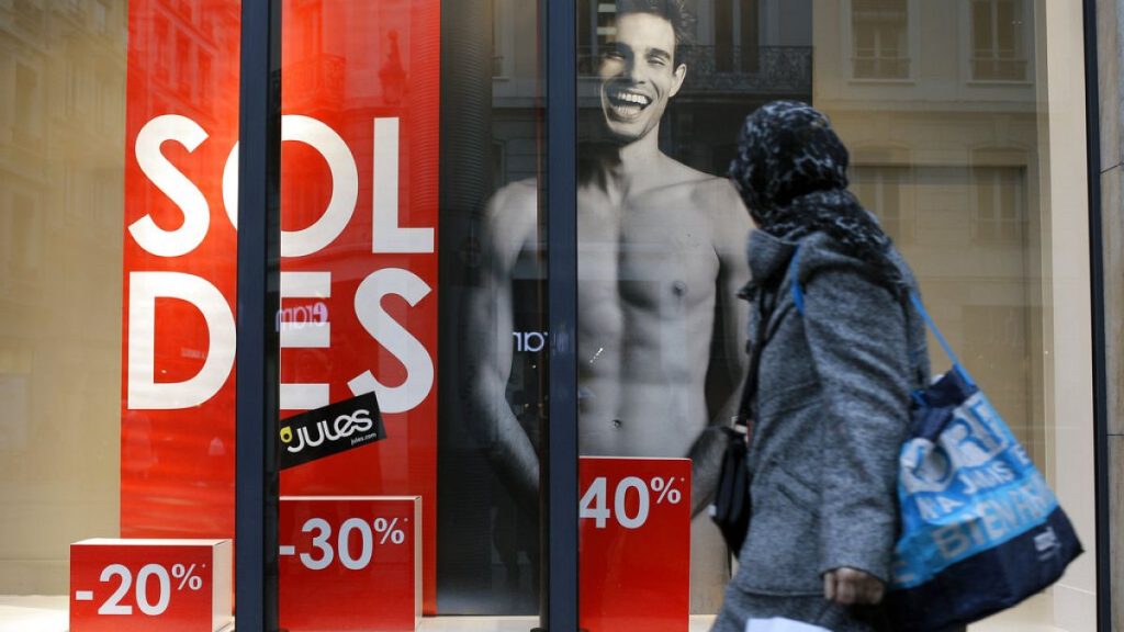 A woman looks at a store advertising for winter sales in Lyon, central France, Thursday, Jan. 7, 2016.