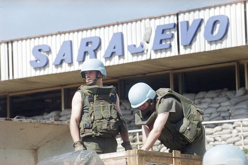 Deux casques bleus français de l'ONU bronzent sous le fort soleil printanier alors qu'ils déchargent une cargaison d'aide humanitaire à l'aéroport de Sarajevo, le jeudi 31 mars 1994.