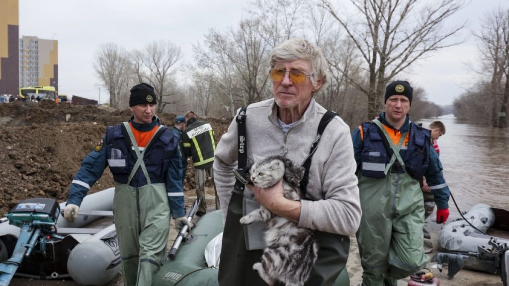 A man holds his cat as he pulls a boat with emergency workers in a flooded area in Orenburg, Russia, Wednesday, April 10, 2024.