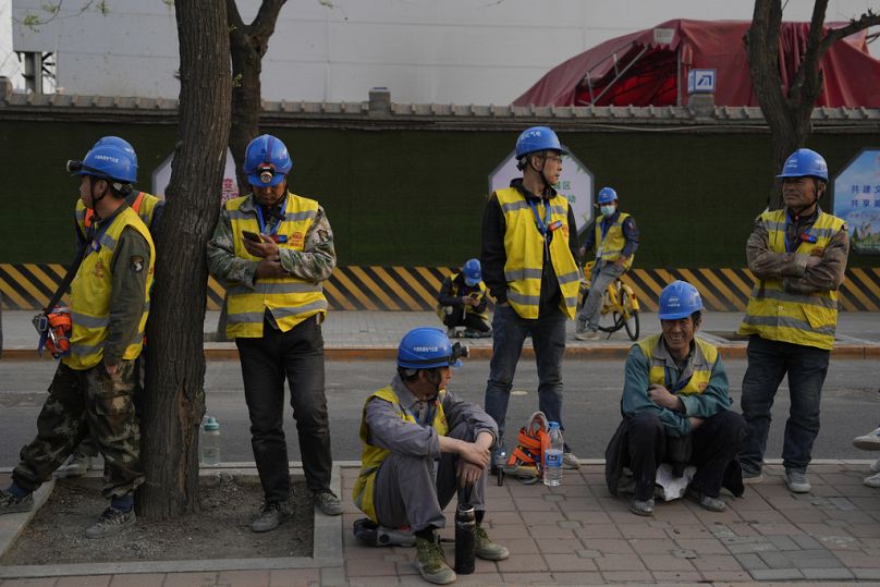 Des ouvriers attendent leur véhicule devant un chantier de construction à Pékin, avril 2024.
