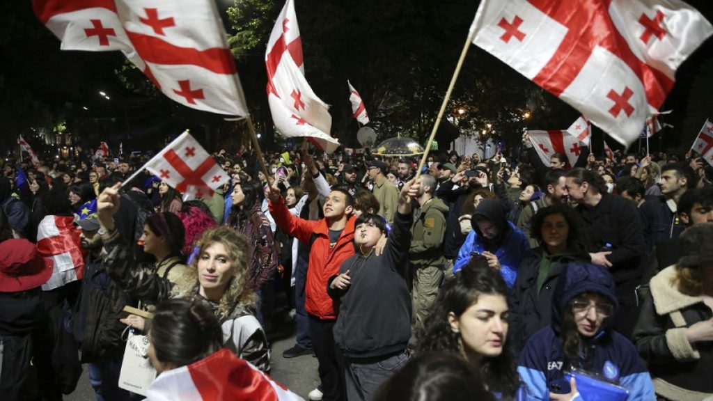 Demonstrators waving Georgian national flags gather in front of the Parliament building during a protest against