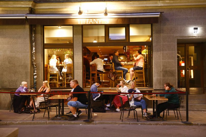 Des gens assis à des tables devant un restaurant à Stockholm, juillet 2021