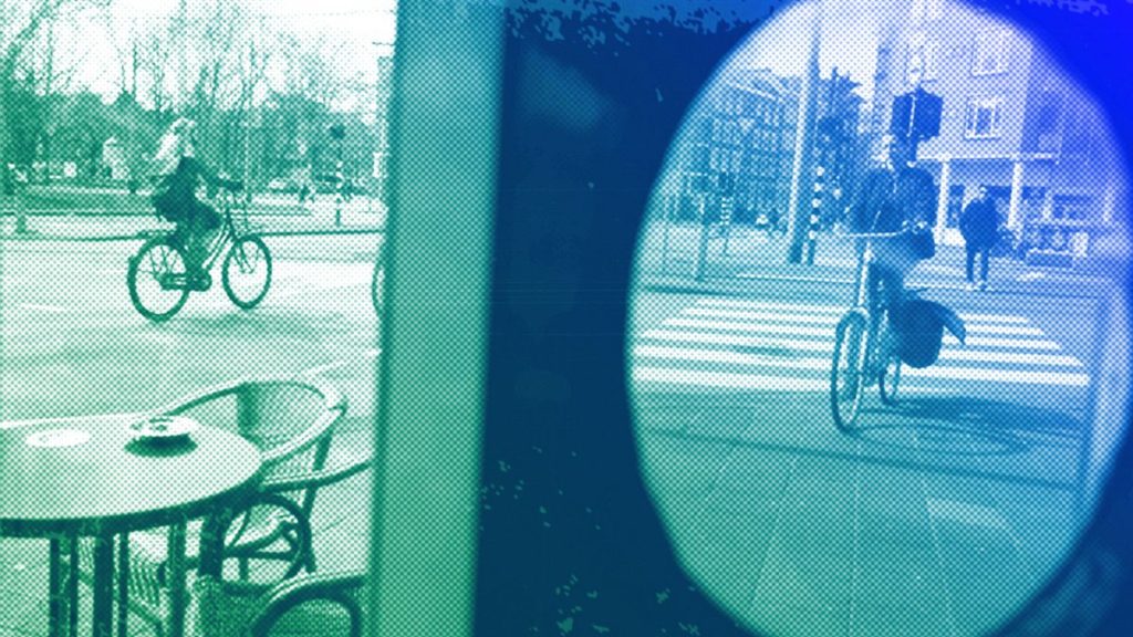 Women ride their bicycle along a street in Amsterdam, April 2017