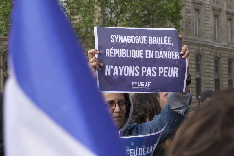 Un manifestant brandit une affiche indiquant « Synagogue incendiée, République en danger, n'ayons pas peur » lors d'un rassemblement à Paris, le 17 mai 2024.