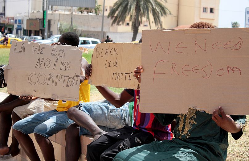 DOSSIER – Des migrants brandissent des pancartes sur lesquelles on peut lire « Black Lives Matter », à gauche, en français, lors d'un rassemblement à Sfax, sur la côte est de la Tunisie, le 7 juillet 2023.