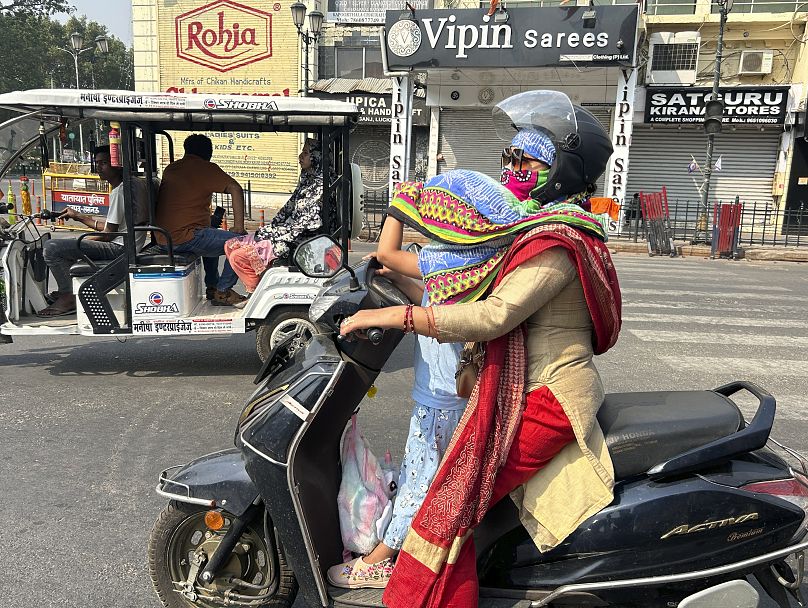 Une cavalière couvre la tête de sa fille avec un foulard pour la protéger de la chaleur intense à Lucknow, en Inde, le 18 mai 2024.