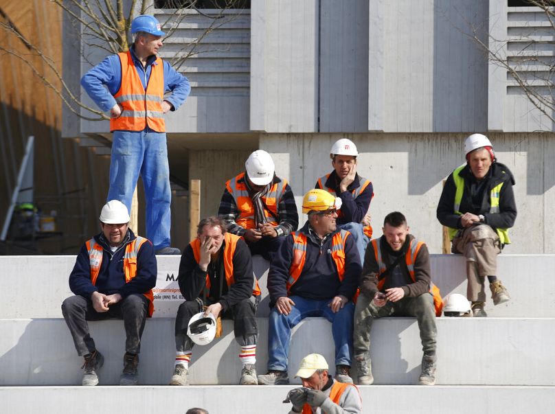 Des ouvriers sont assis près des pavillons en construction lors de la visite du Premier ministre italien Matteo Renzi sur le site de l'Expo de Rho, en mars 2015.