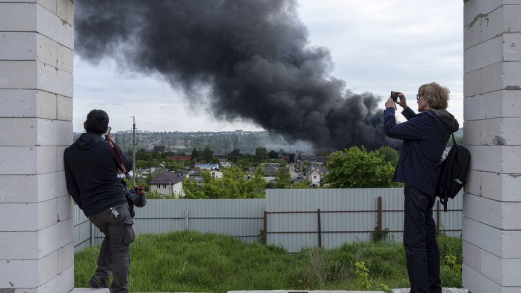 Foreign journalists report from an observation point while smoke rises after a Russian attack in Kharkiv, Ukraine, Friday, May 17, 2024.