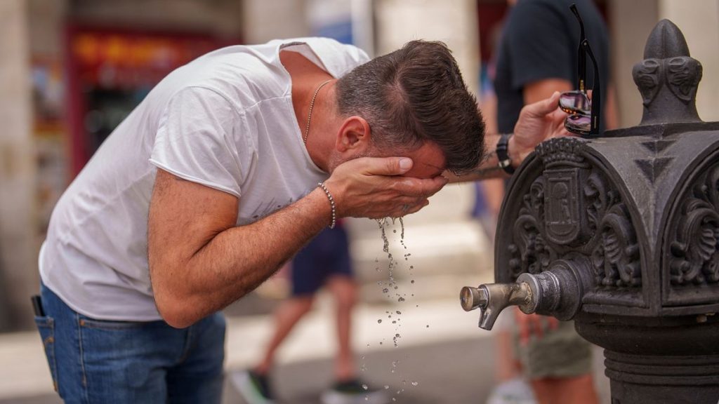 A man cool off in a fountain during a hot and sunny day of summer in Madrid, Spain.