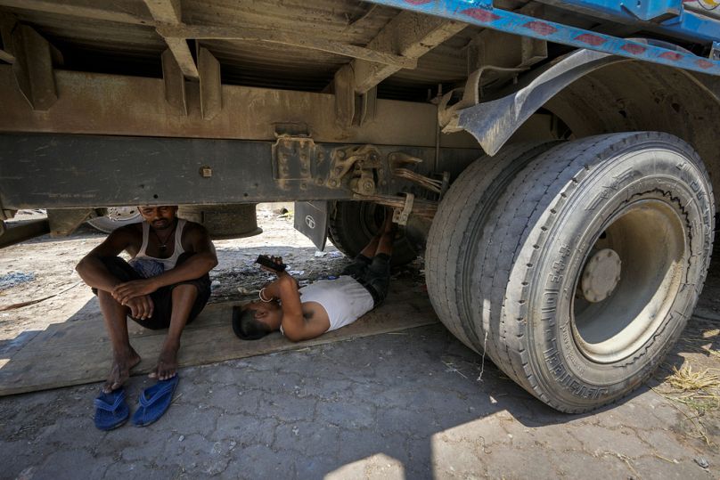 Des ouvriers se réfugient sous un camion garé contre la chaleur torride, à Guwahati, en Inde.