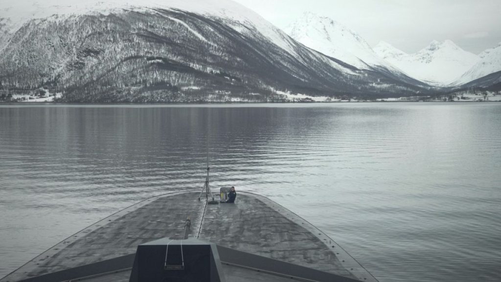 A French sailor sits at the bow of the French navy frigate Normandie during a patrol in a Norwegian fjord, north of the Arctic circle, Friday March 8, 2024.