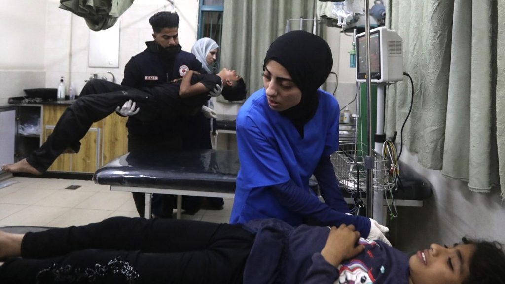 Palestinian medics treat a wounded person as the other one carries a young wounded in the Israeli bombardment of the Gaza Strip at the Kuwaiti Hospital in Rafah refugee camp,