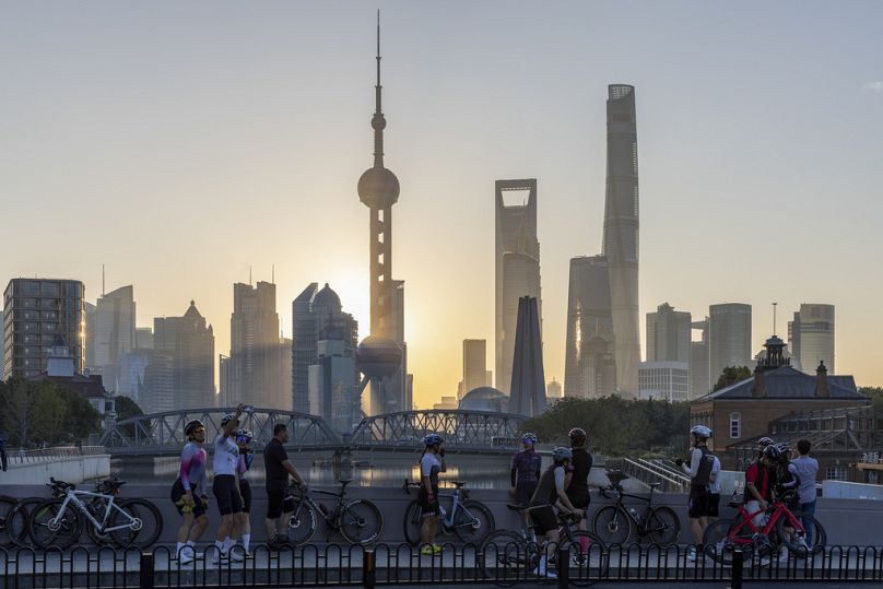 Des cyclistes se reposent devant le lever du soleil à Pudong, le centre financier et commercial de la Chine, à Shanghai, en novembre 2023.
