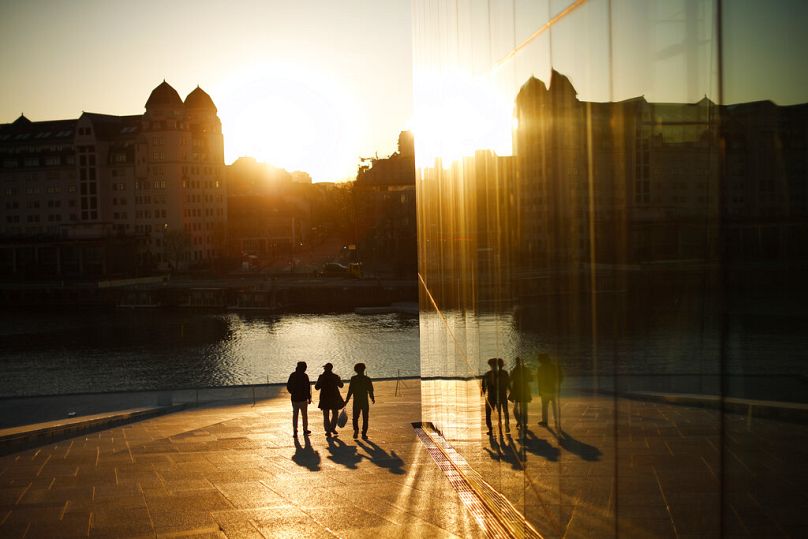 Des gens marchent à l'Opéra au coucher du soleil dans le centre-ville d'Oslo, avril 2021