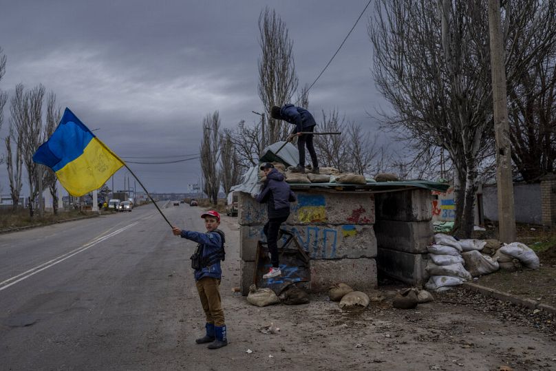 Des enfants ukrainiens jouent à un poste de contrôle abandonné à Kherson, novembre 2022