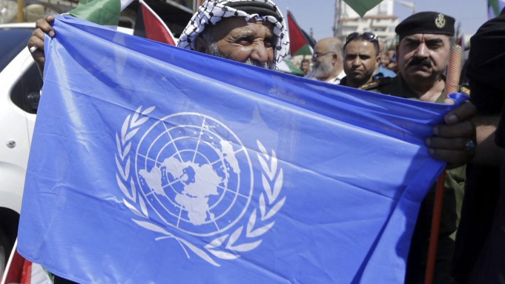 A Palestinian holds U.N flag in a refugee camp near Bethehem, West Bank, Wednesday, Sept. 26, 2018. (AP Photo/Mahmoud Illean)