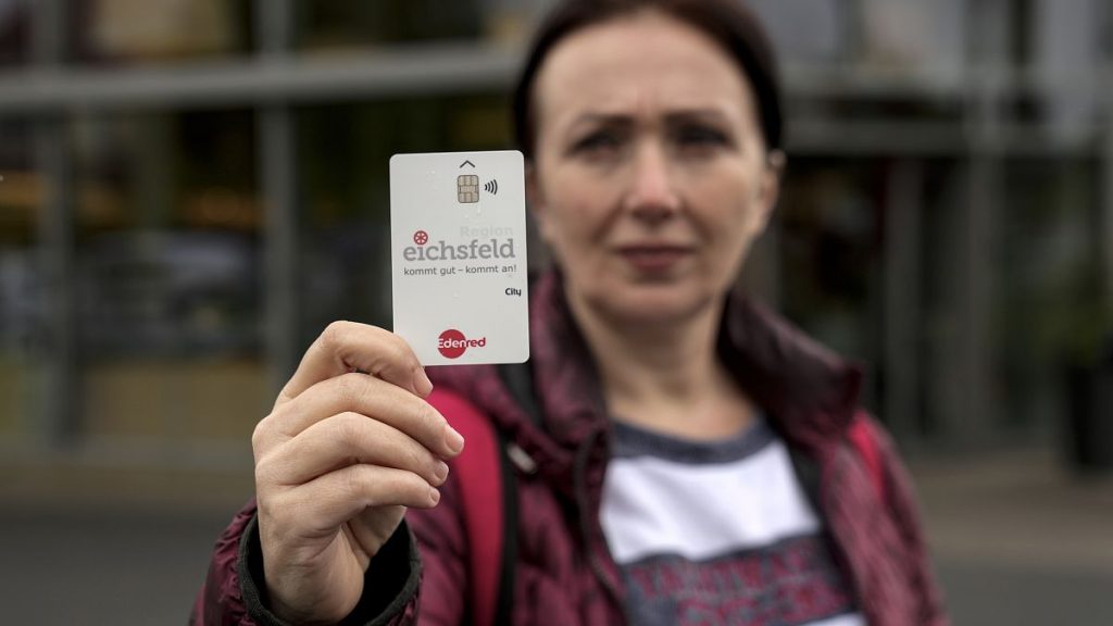 Erdina Laca, a 45-year-old asylum seeker, shows her special payment card in front of a grocery store, in Eichsfeld, Germany, Wednesday, April 24, 2024.