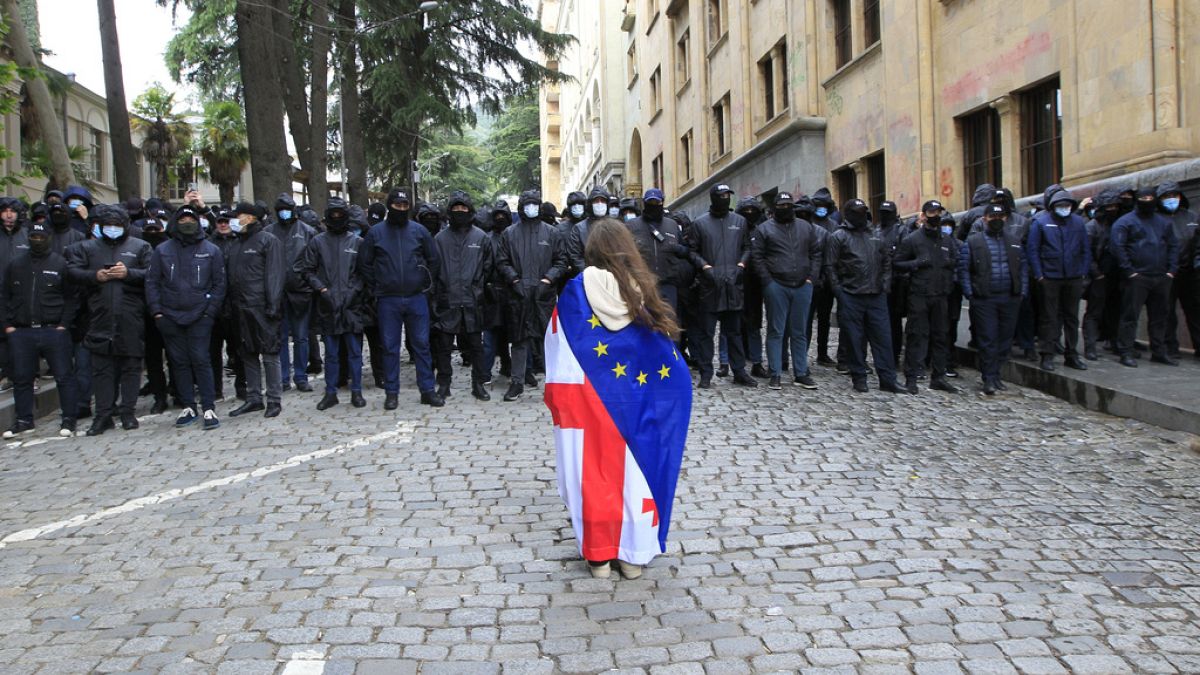 A woman holds a Georgian national and an EU flags while protesting