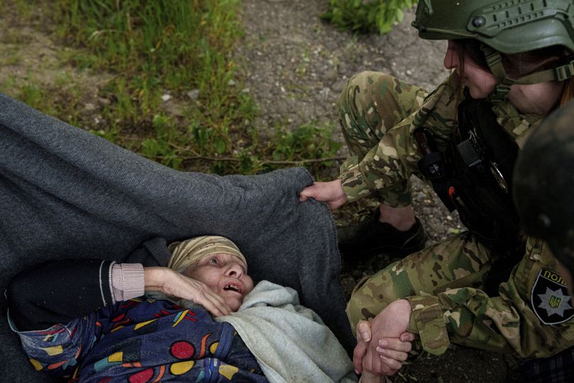 Un policier parle à une femme âgée après une frappe aérienne russe lors d'une évacuation à Vovchansk, en Ukraine