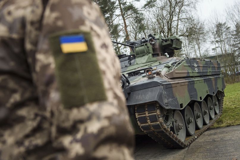 Un soldat ukrainien se tient devant un véhicule de combat d'infanterie Marder dans la zone d'entraînement des forces allemandes de la Bundeswehr à Munster, le 20 février 2023.