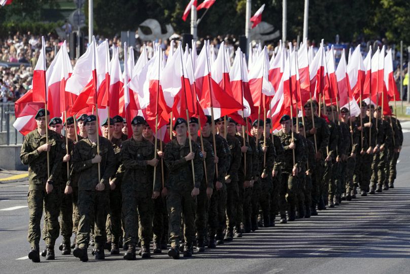 Les membres des nouvelles troupes volontaires de défense territoriale défilent avec les drapeaux nationaux de la Pologne