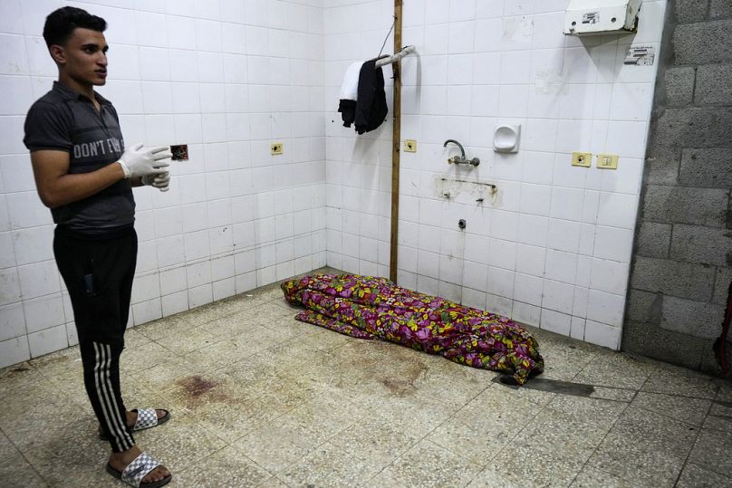 Un médecin palestinien se tient près d'un corps en attendant d'autres personnes tuées lors du bombardement israélien de la bande de Gaza, à la morgue de l'hôpital Al Aqsa, dimanche 26 mai 2024.