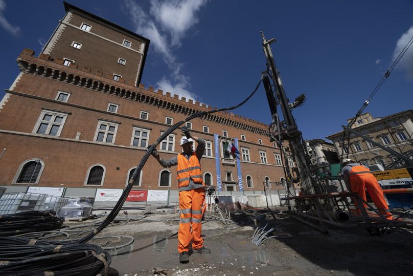 Des ouvriers injectent des produits chimiques réactifs pour consolider le chantier de construction de la Piazza Venezia, dans le centre de Rome, le 23 mai 2024.