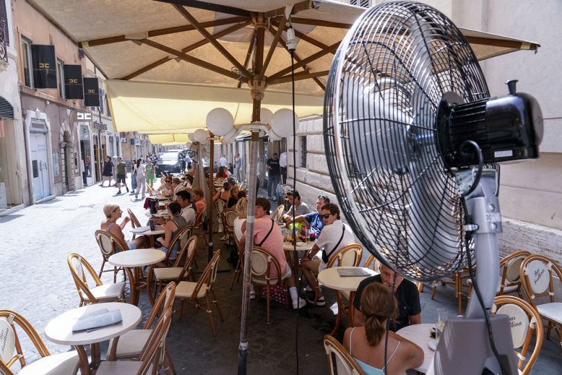 Les clients apprécient le soulagement d'un fan alors qu'ils sont assis dans un bar du centre-ville de Rome.