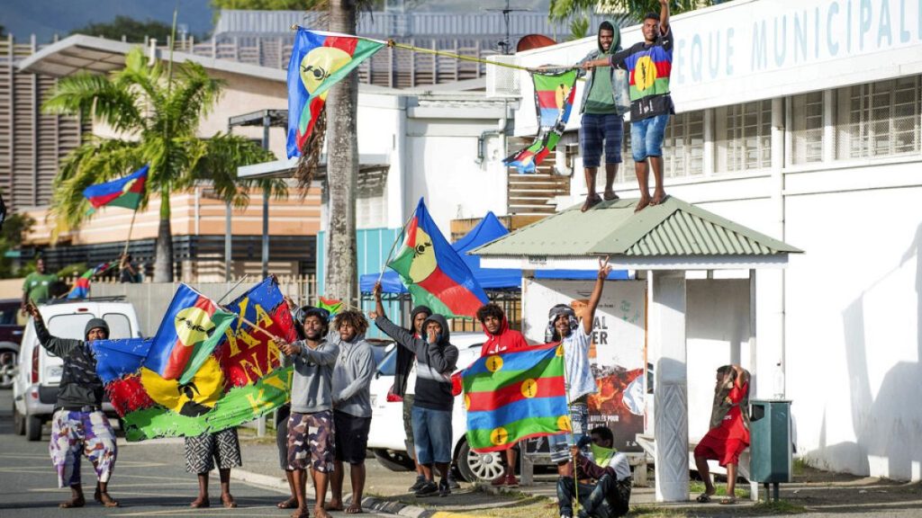 Independence supporters demonstrate with the Kanak flag outside a voting station in the Riviere Salee district of Noumea, New Caledonia, Sunday, Oct.4, 2020 AP Photo/Mathurin