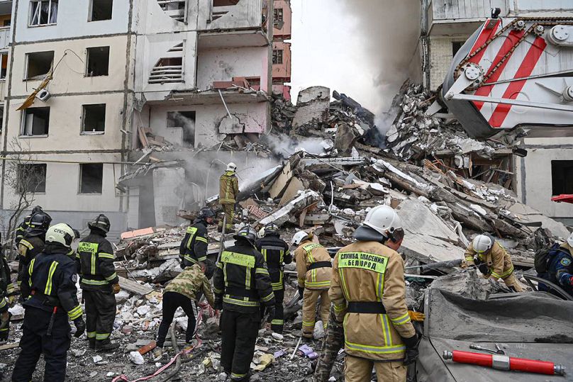 Des employés des services d'urgence russes travaillent sur les lieux d'un immeuble partiellement effondré après une attaque de missile par les forces armées ukrainiennes à Belgorod
