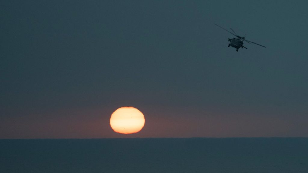 An MH-60S Seahawk helicopter flies back to the U.S.S. aircraft carrier Dwight D. Eisenhower, also known as the