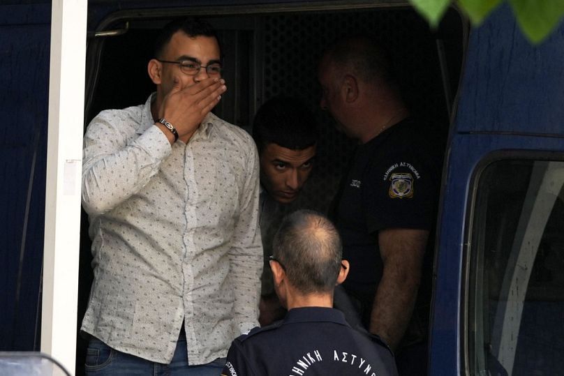 L'un des neuf Égyptiens accusés d'avoir causé le naufrage qui a tué des centaines de migrants salue alors qu'il est conduit par la police vers un palais de justice à Kalamata, le mardi 21 mai 2024.