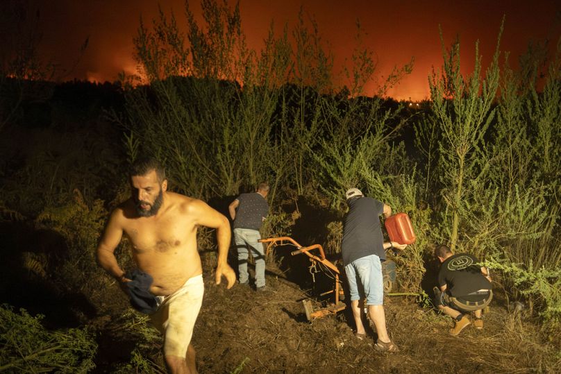 Les résidents locaux tentent de nettoyer une forêt pour l'empêcher de prendre feu alors que le feu progresse à La Orotava à Tenerife, dans les îles Canaries, en Espagne, en août 2023.