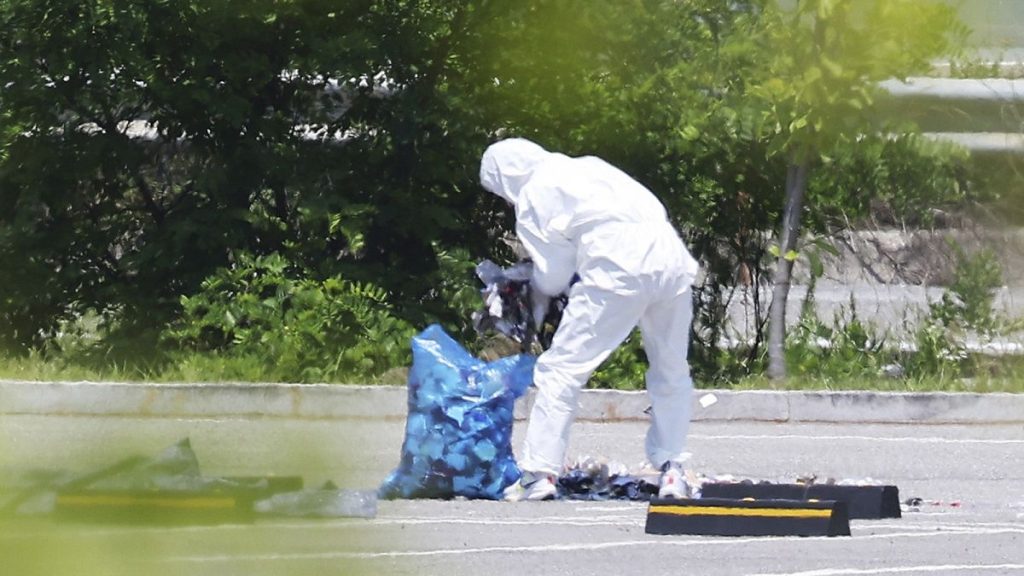 An officer wearing protective gear collects the trash from a balloon presumably sent by North Korea, in Siheung, South Korea, 2 June 2024