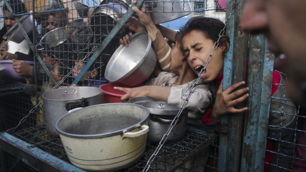 FILE - Palestinians line up to receive meals at Jabaliya refugee camp in the Gaza Strip, March 18, 2024