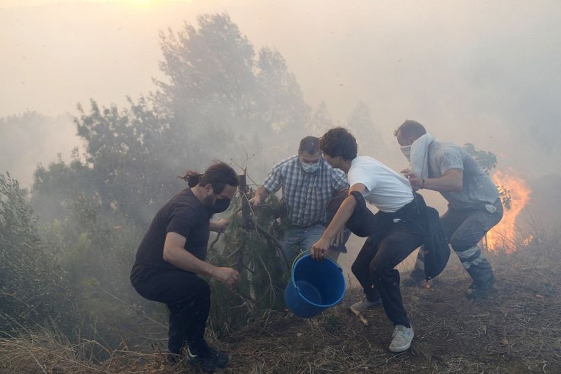 Les résidents locaux utilisent des seaux d'eau pour tenter de ralentir les flammes à l'approche de leurs maisons à Alcabideche, à l'extérieur de Lisbonne, au Portugal, en juillet 2023.