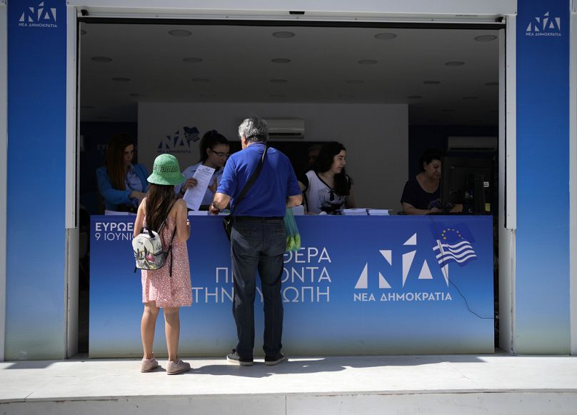 Un homme se tient devant un kiosque électoral du parti au pouvoir de la Nouvelle Démocratie à Athènes, en Grèce, le vendredi 7 juin 2024.