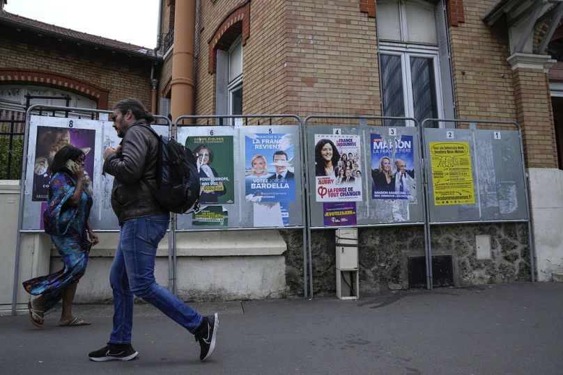 Des gens passent devant une rangée d'affiches de campagne pour les prochaines élections européennes à Courbevoie, à l'ouest de Paris, le jeudi 6 juin 2024.