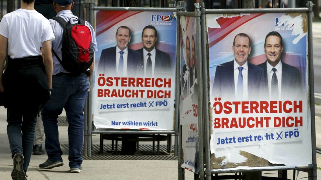 People pass by damaged election posters showing former Austrian Vice Chancellor and Interior Minister Heinz-Christian Strache, right in Vienna, Sunday, May 26, 2019.