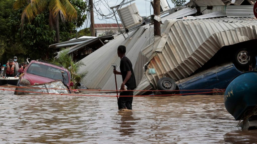 In this Nov. 6, 2020, file photo, a resident walking through a flooded street looks back at storm damage caused by Hurricane Eta in Planeta, Honduras.