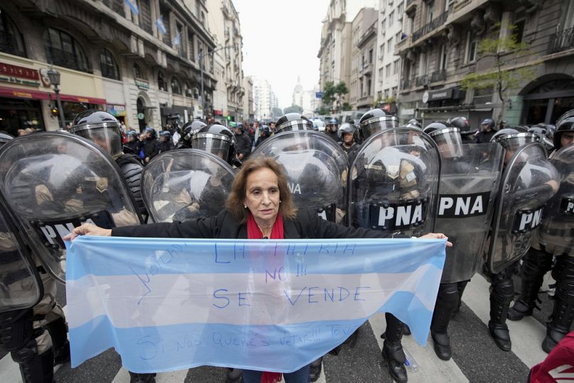 Un manifestant antigouvernemental tient un drapeau argentin devant la police près du Congrès où les législateurs débattent d'un projet de loi de réforme promu par le président argentin Javier Milei à Buenos Aires.