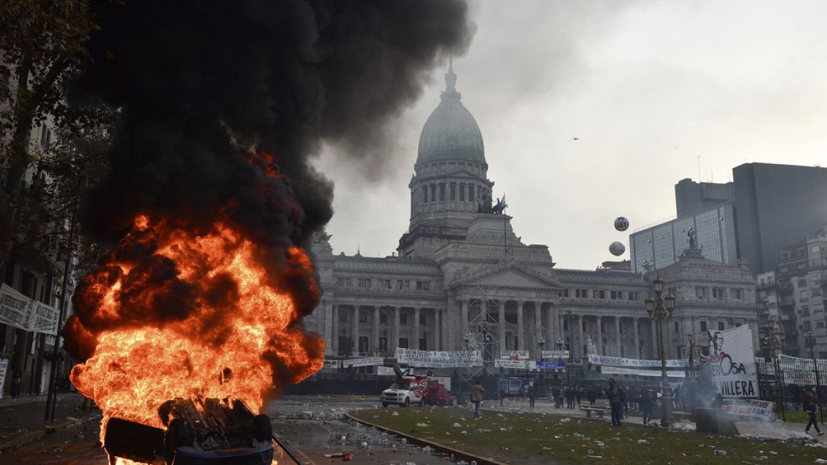 A car burns during clashes between police and protesters outside Congress  in Buenos Aires, Argentina, Wednesday, June 12, 2024.