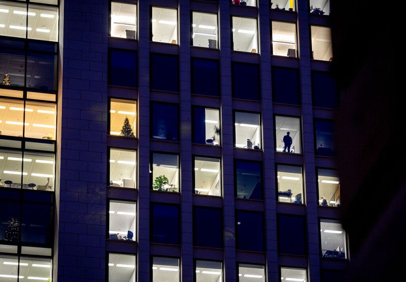 Un homme regarde par la fenêtre d’un immeuble de bureaux à Francfort, décembre 2022