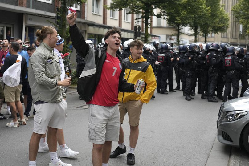 Les fans de football anglais applaudissent devant la police avant le match du groupe C entre la Serbie et l'Angleterre à l'Euro 2024 à Gelsenkirchen, en Allemagne, le dimanche 16 juin 2024.